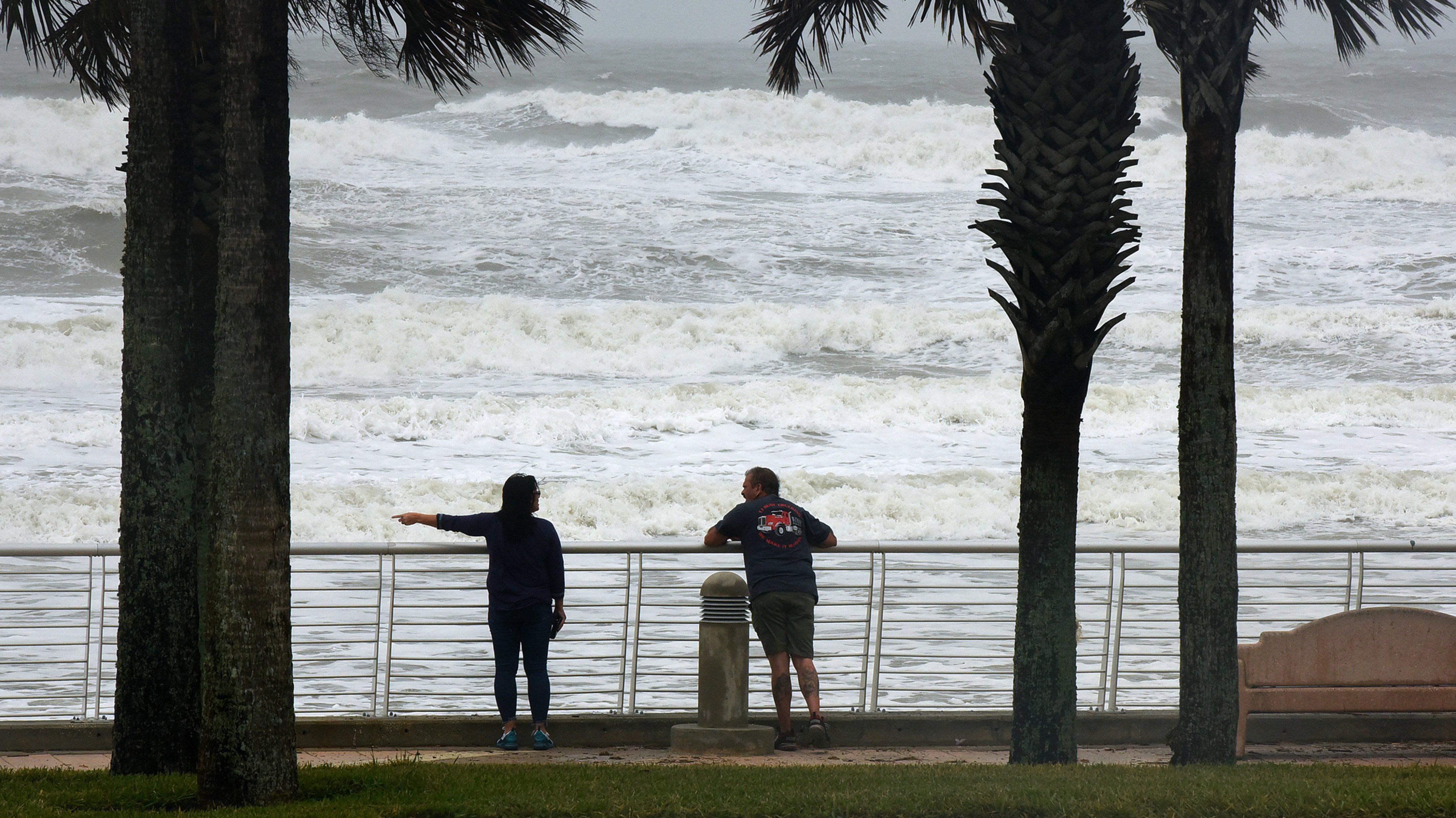 A couple watches as waves crash near the pier at Daytona