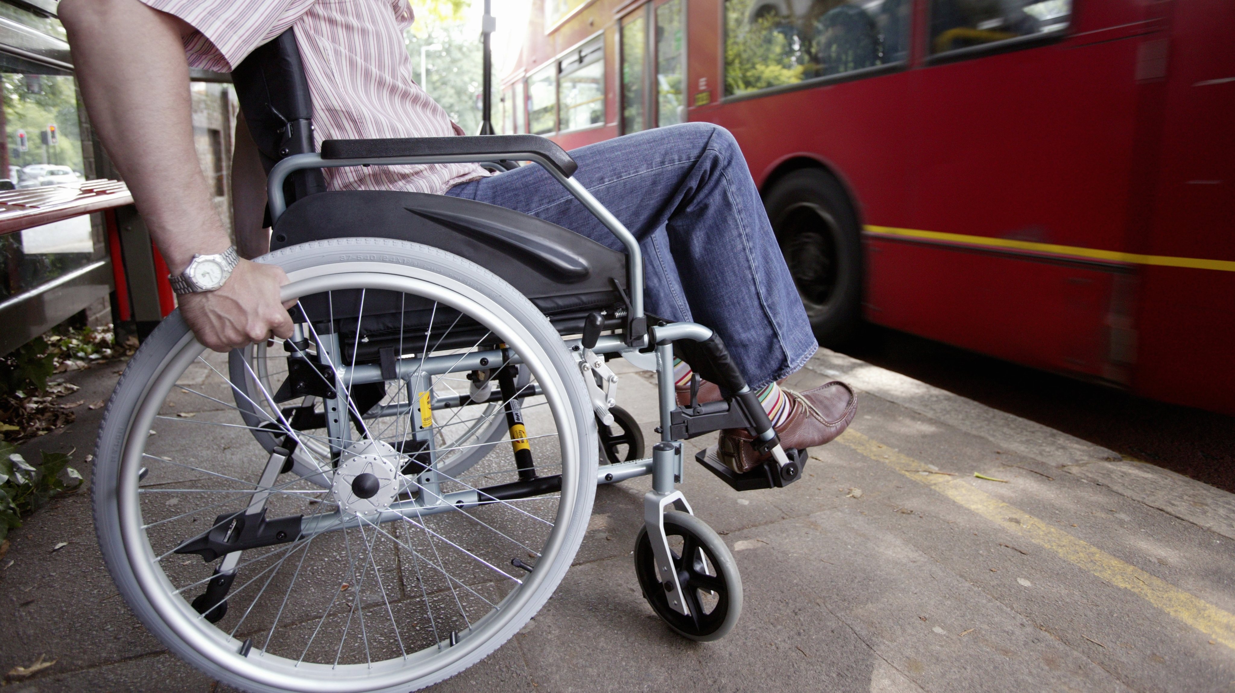 England, London, Disabled man in wheelchair at bus stop