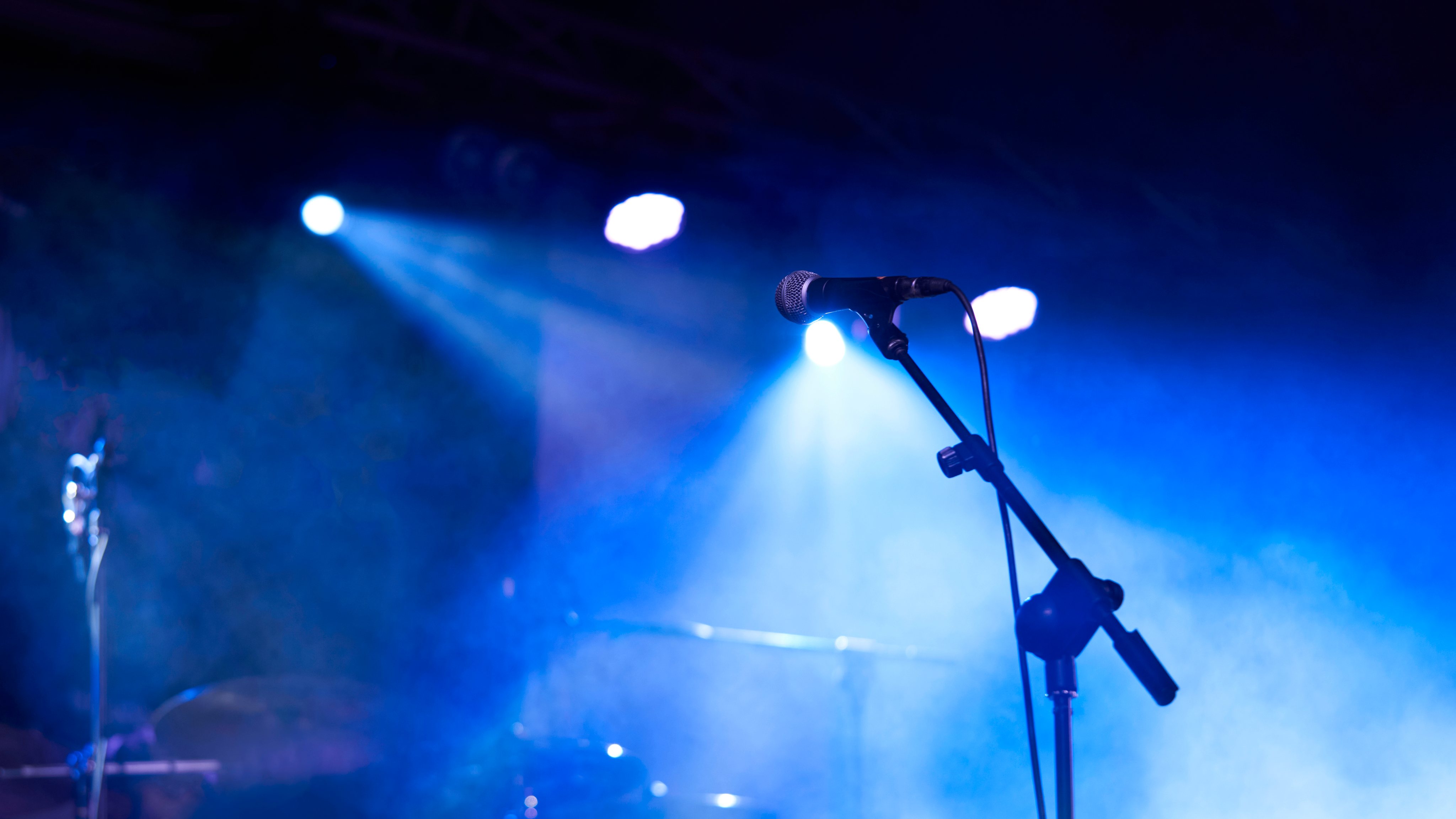 Rear view low angle view of a microphone and spotlights on stage at a live concert with musical instruments background