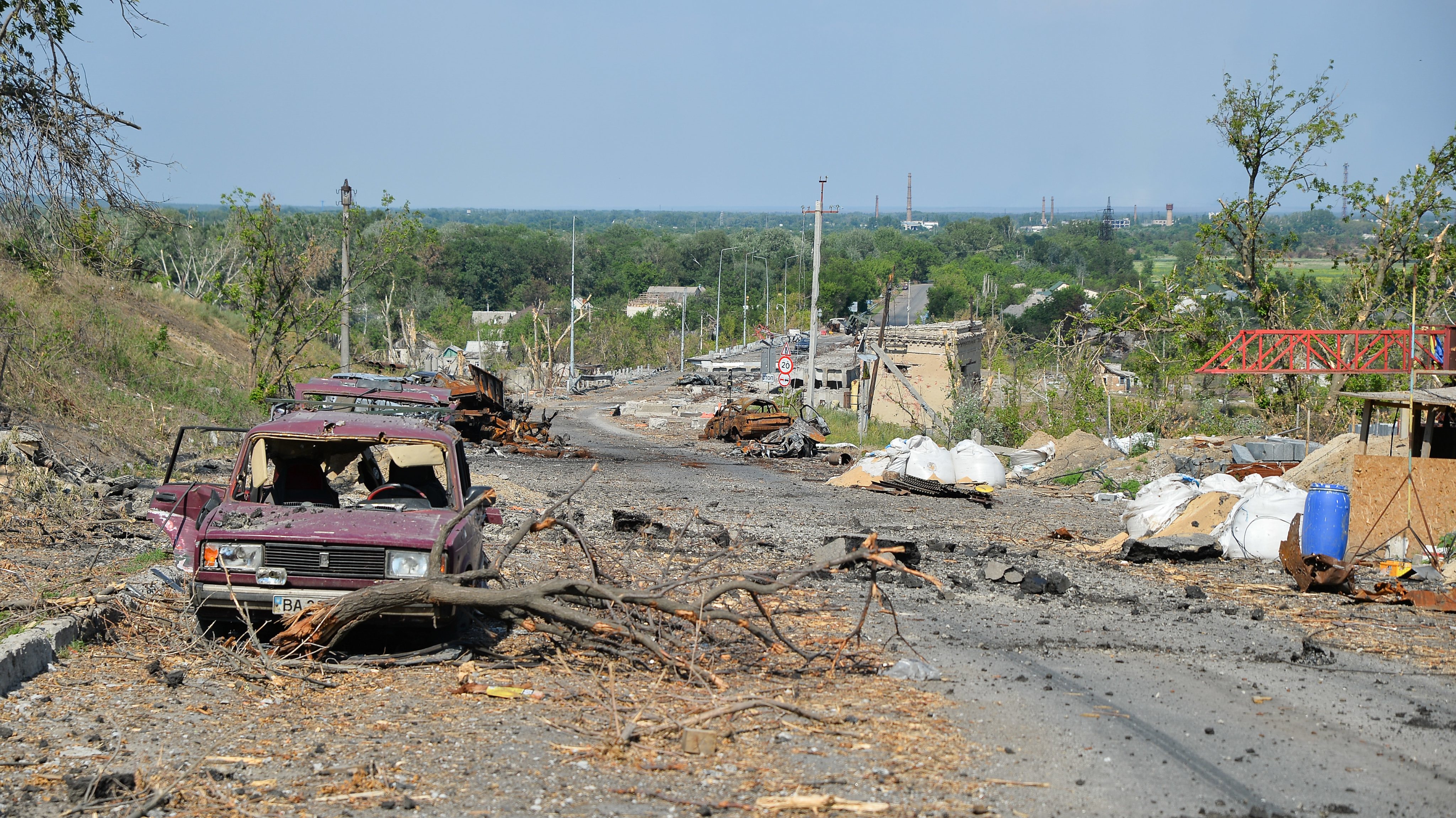 Debris and destroyed cars are seen along the street in