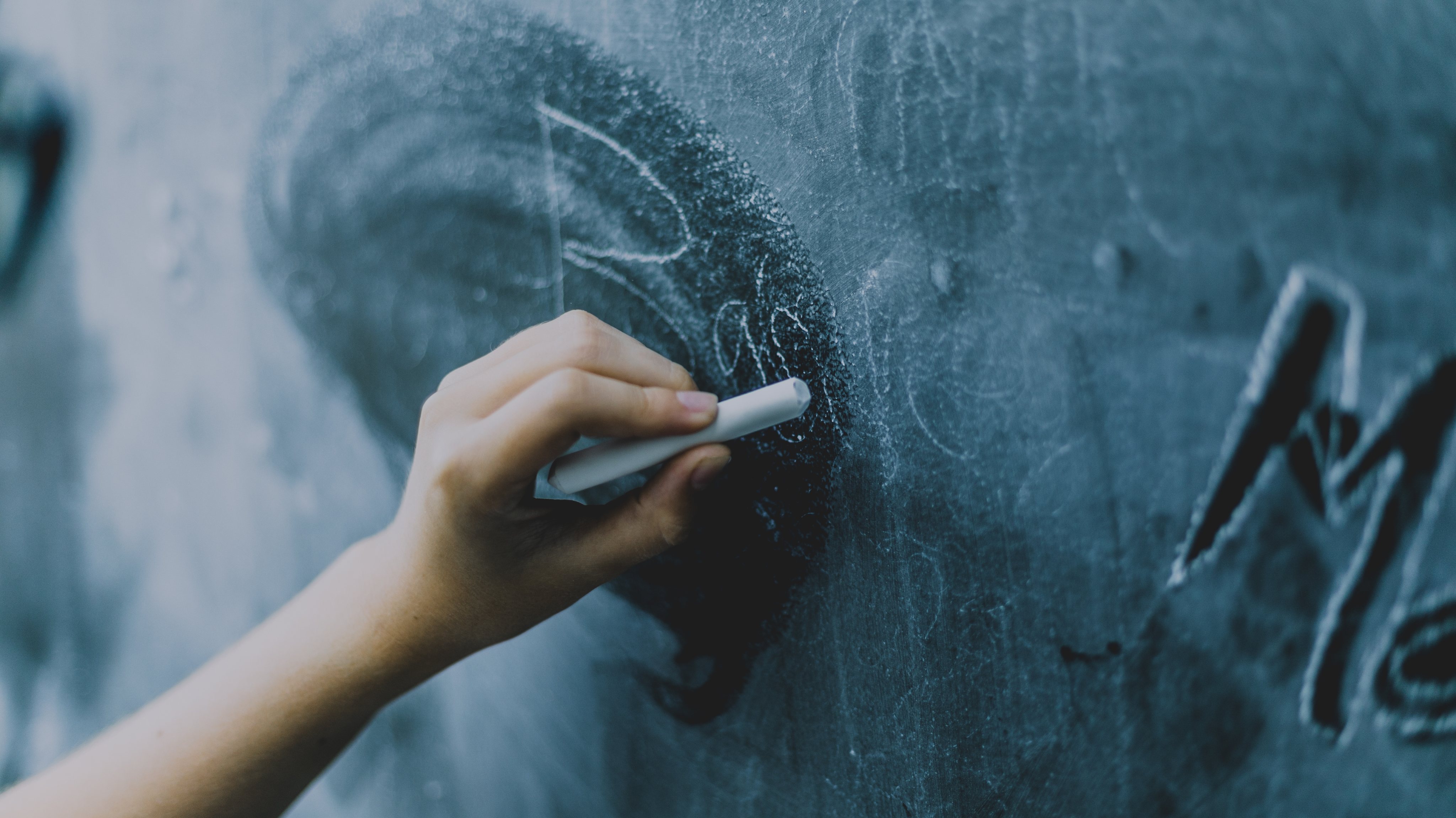 hands writing in chalkboard
