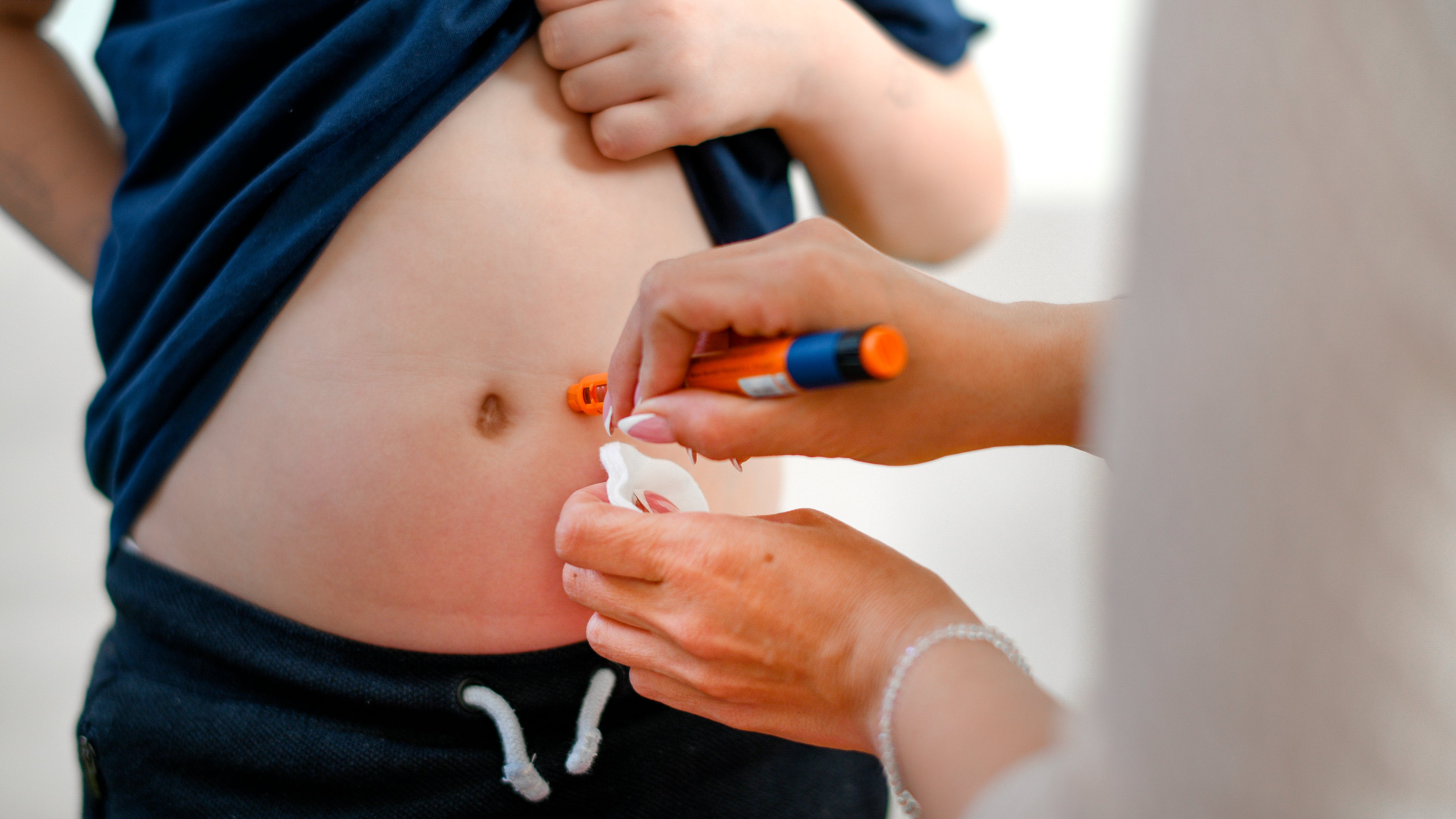 Boy taking an insulin shot at stomach