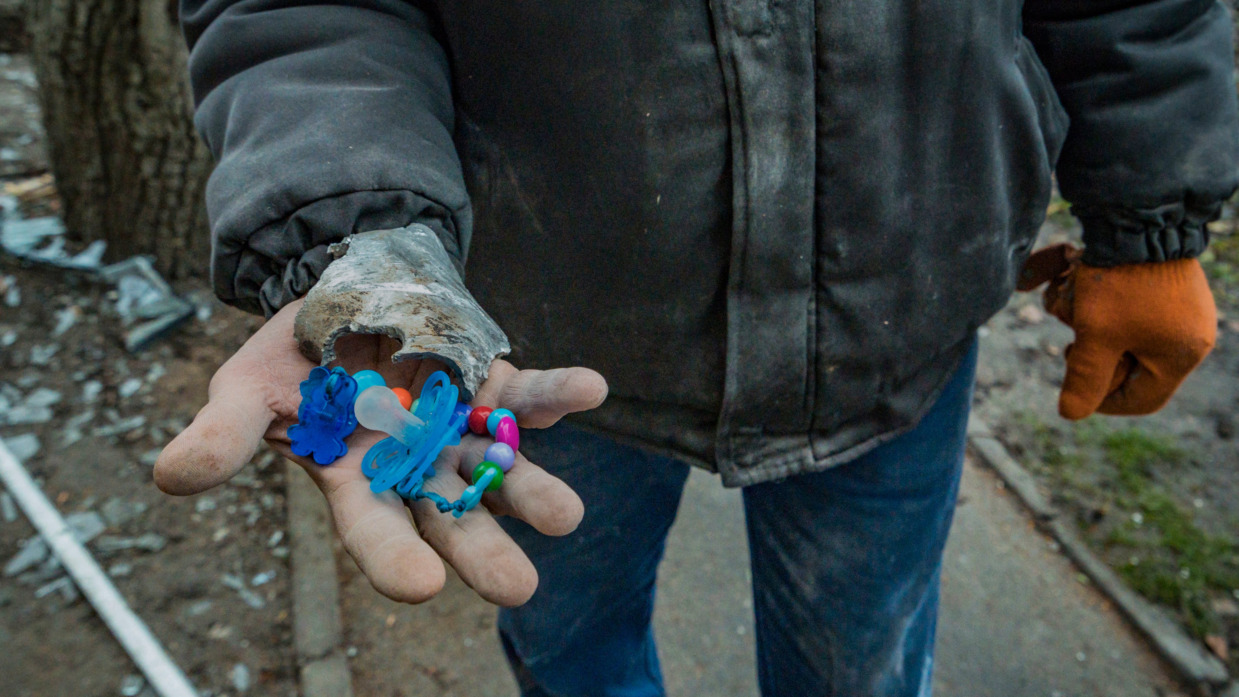 Um trabalhador mostra uma chupeta e uma peça de um míssil encontrados nos escombros da maternidade em Vilnyansk, Zaporíjia