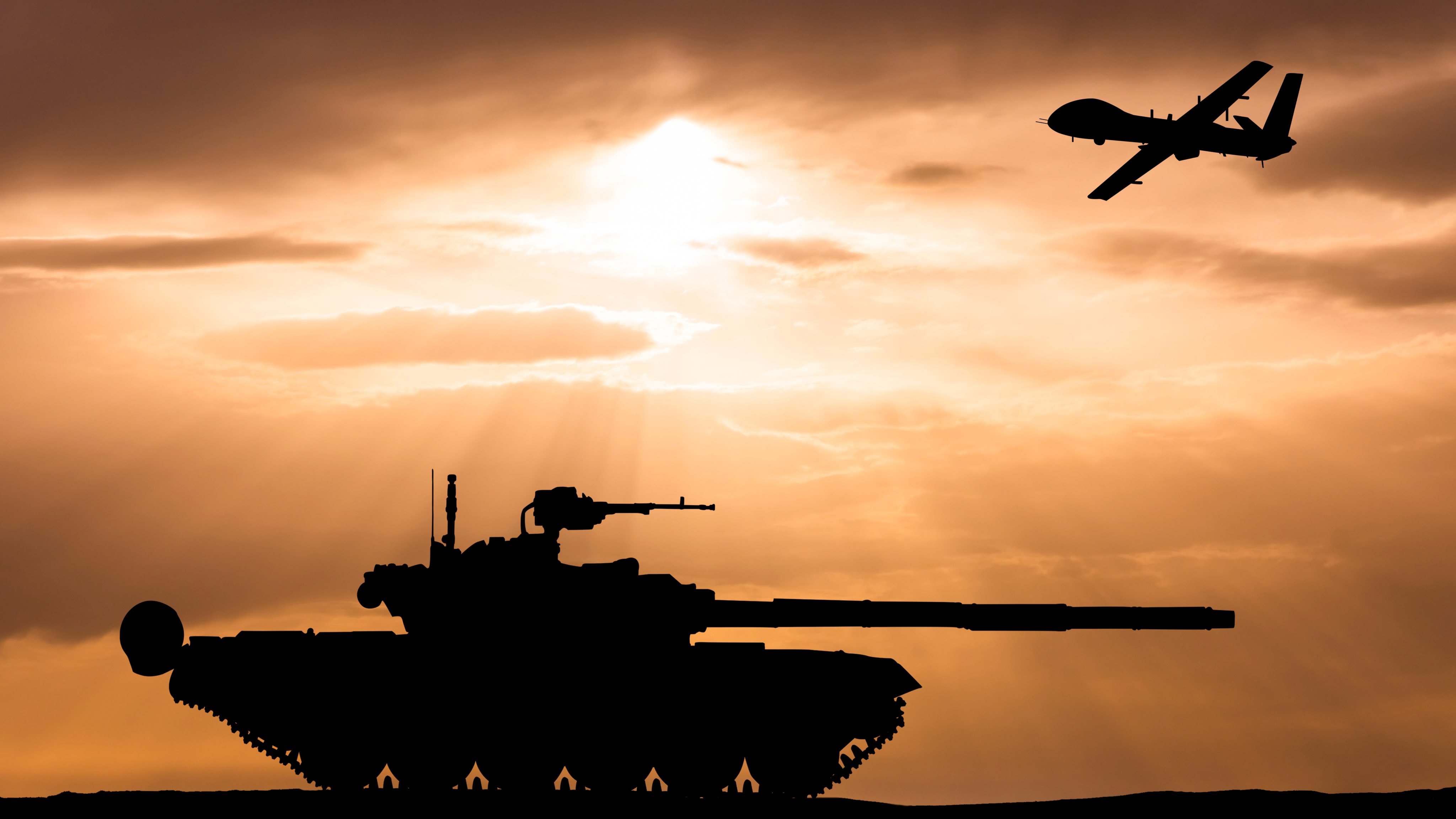 Armored tank and combat drone on the background of the sunset sky