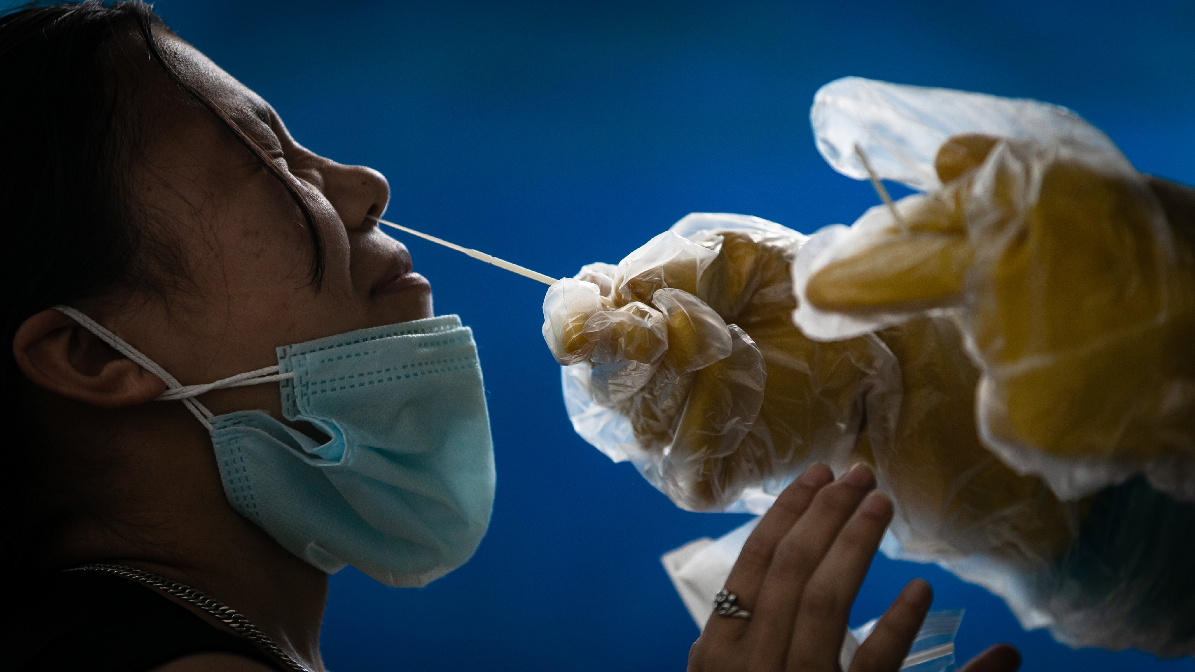 A health worker collects the nasal swab from a girl for