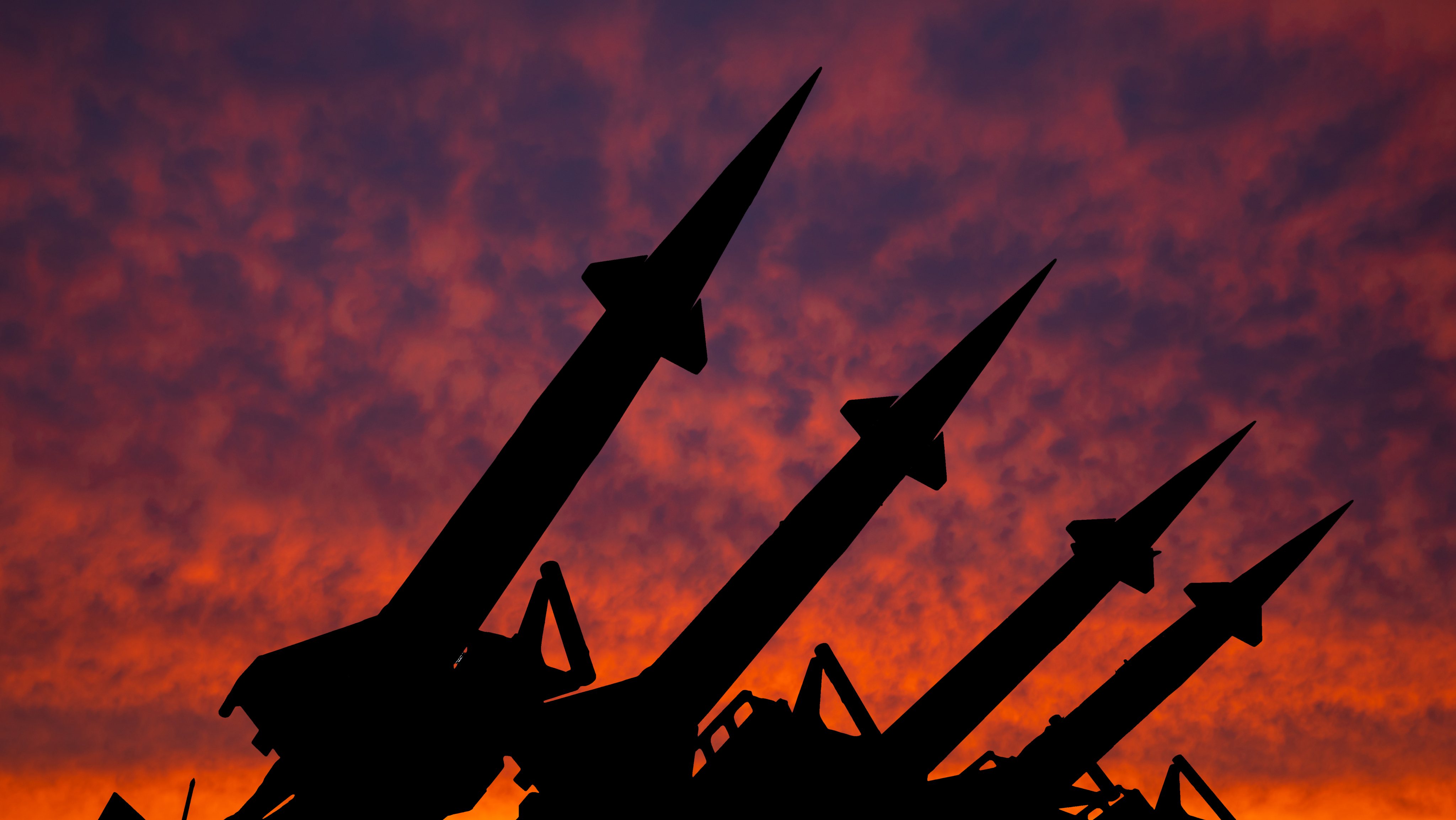 Four rockets of anti-aircraft missile system are directed upwards against the background of sunset