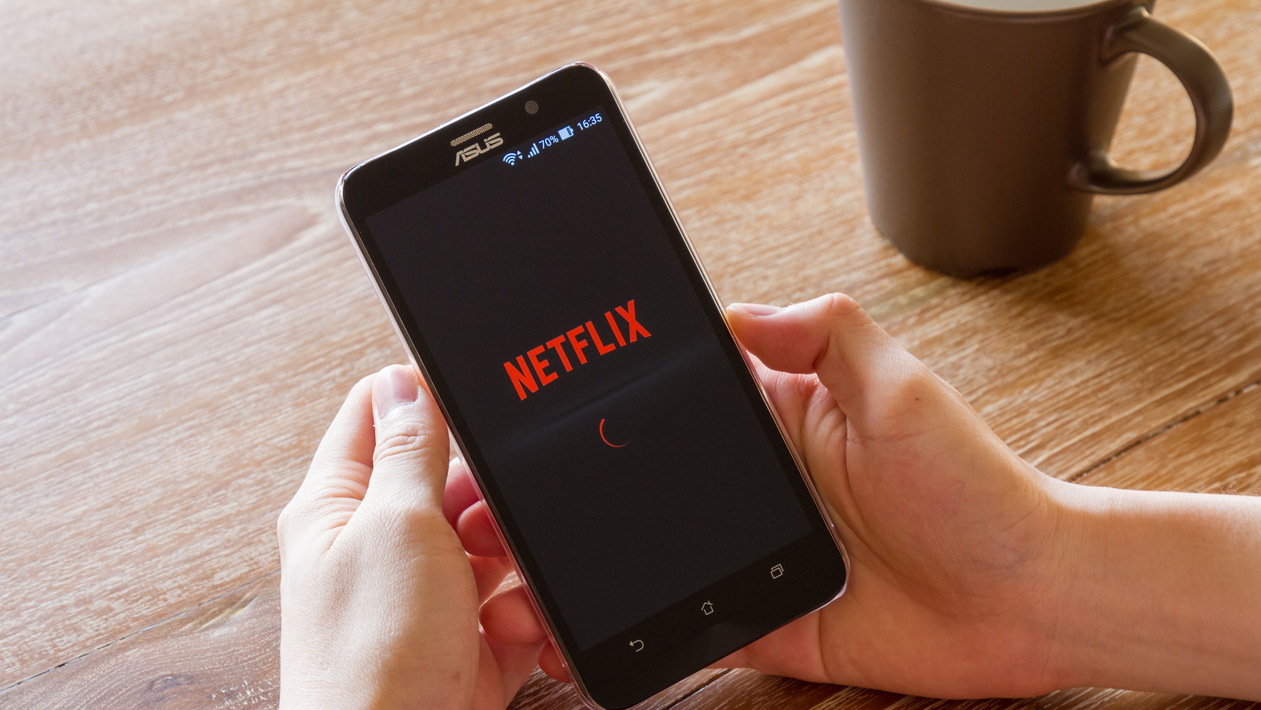 man hand holding screen shot of Netflix application