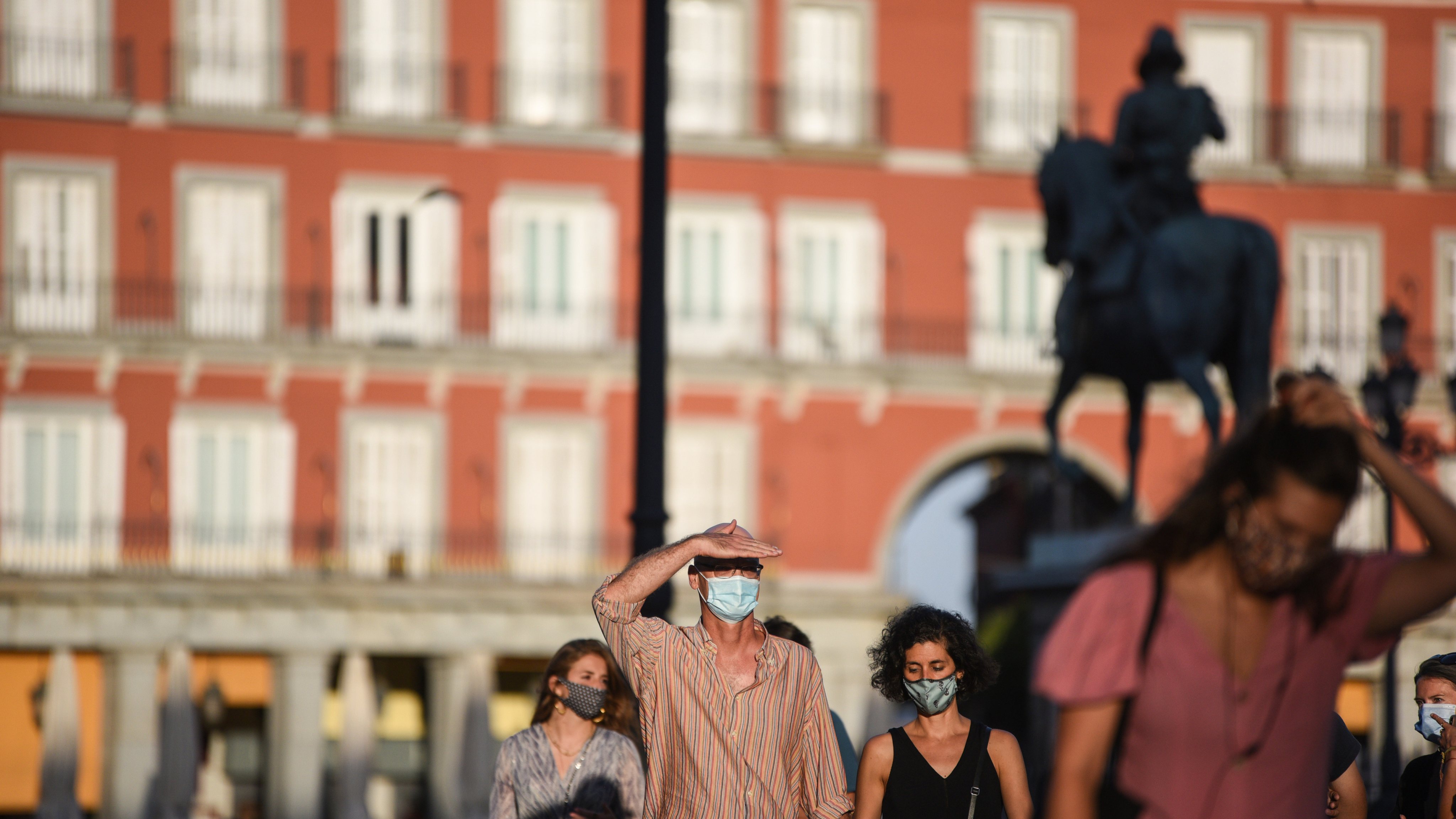 People walking along Plaza Mayor while wearing face masks as