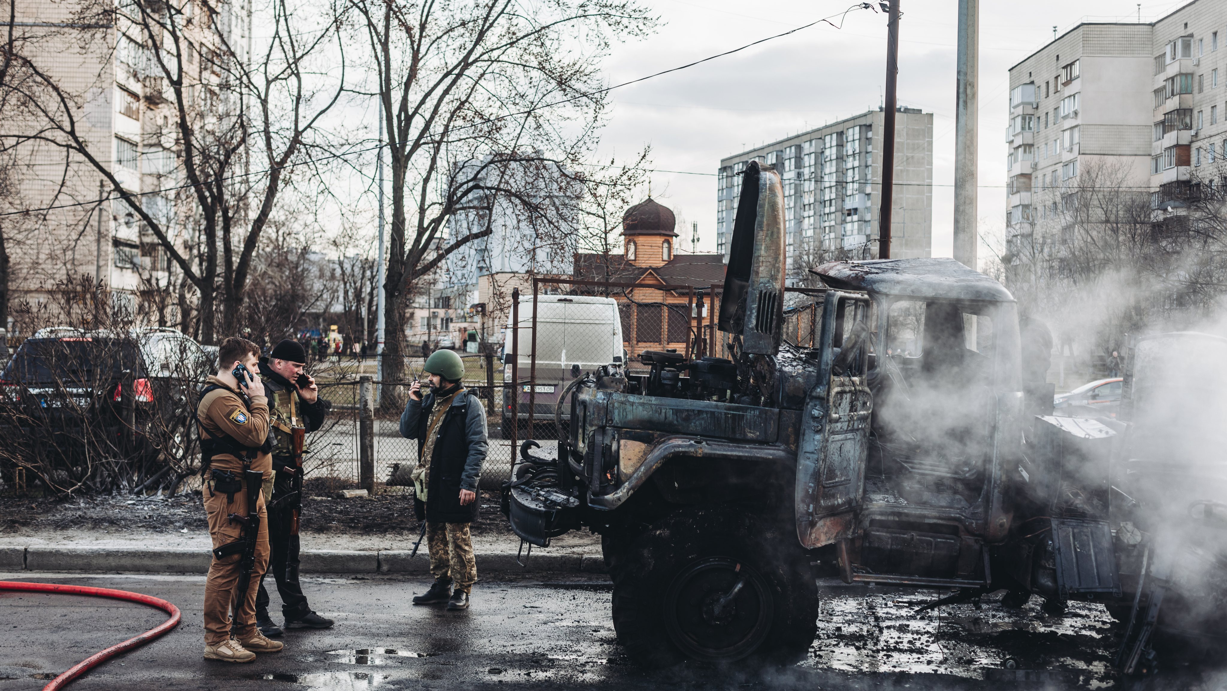 Soldados ucranianos olham para o seu veículo militar incendidado
