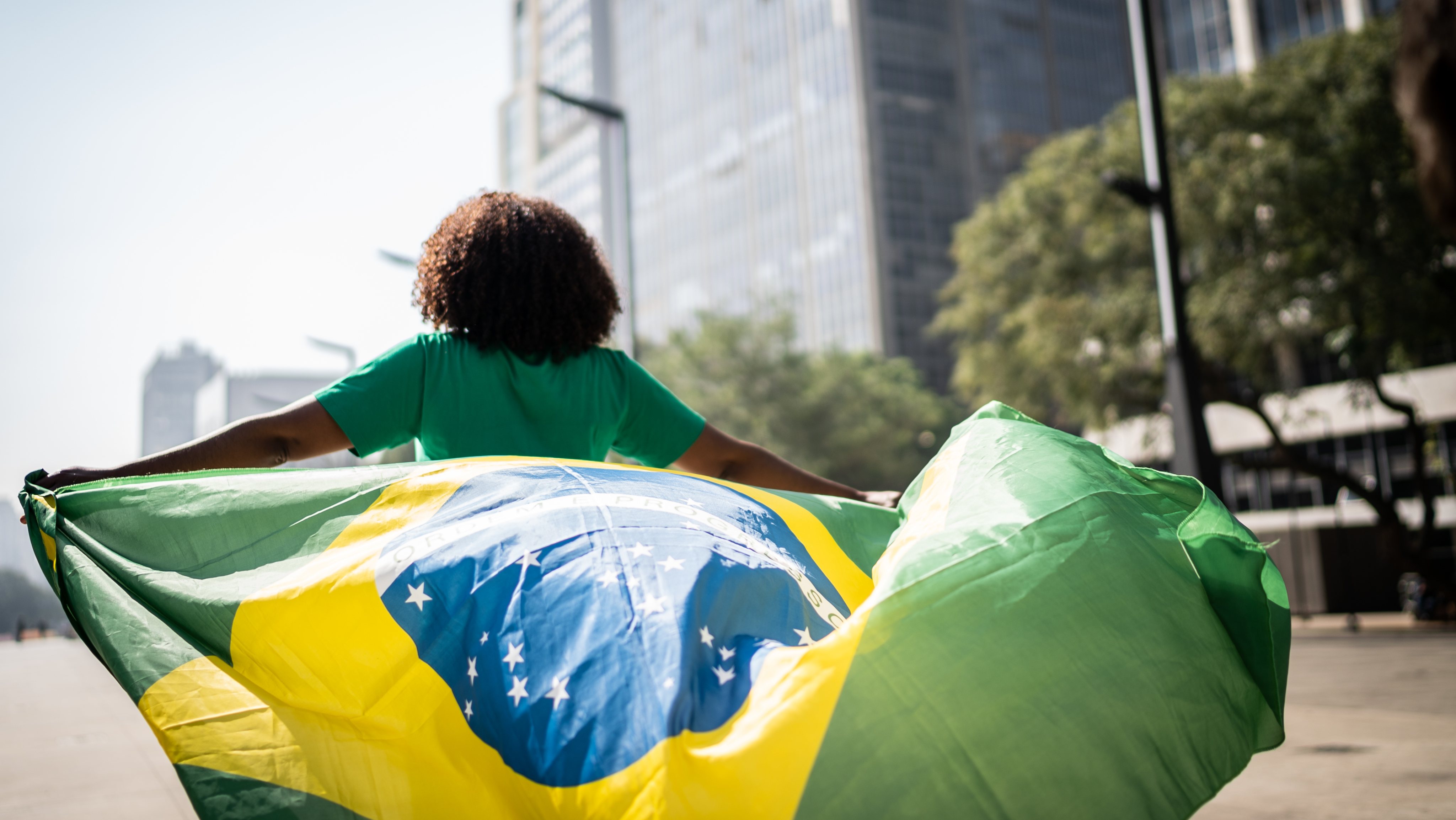 Brazilian fan walking and holding a brazilian flag on the city