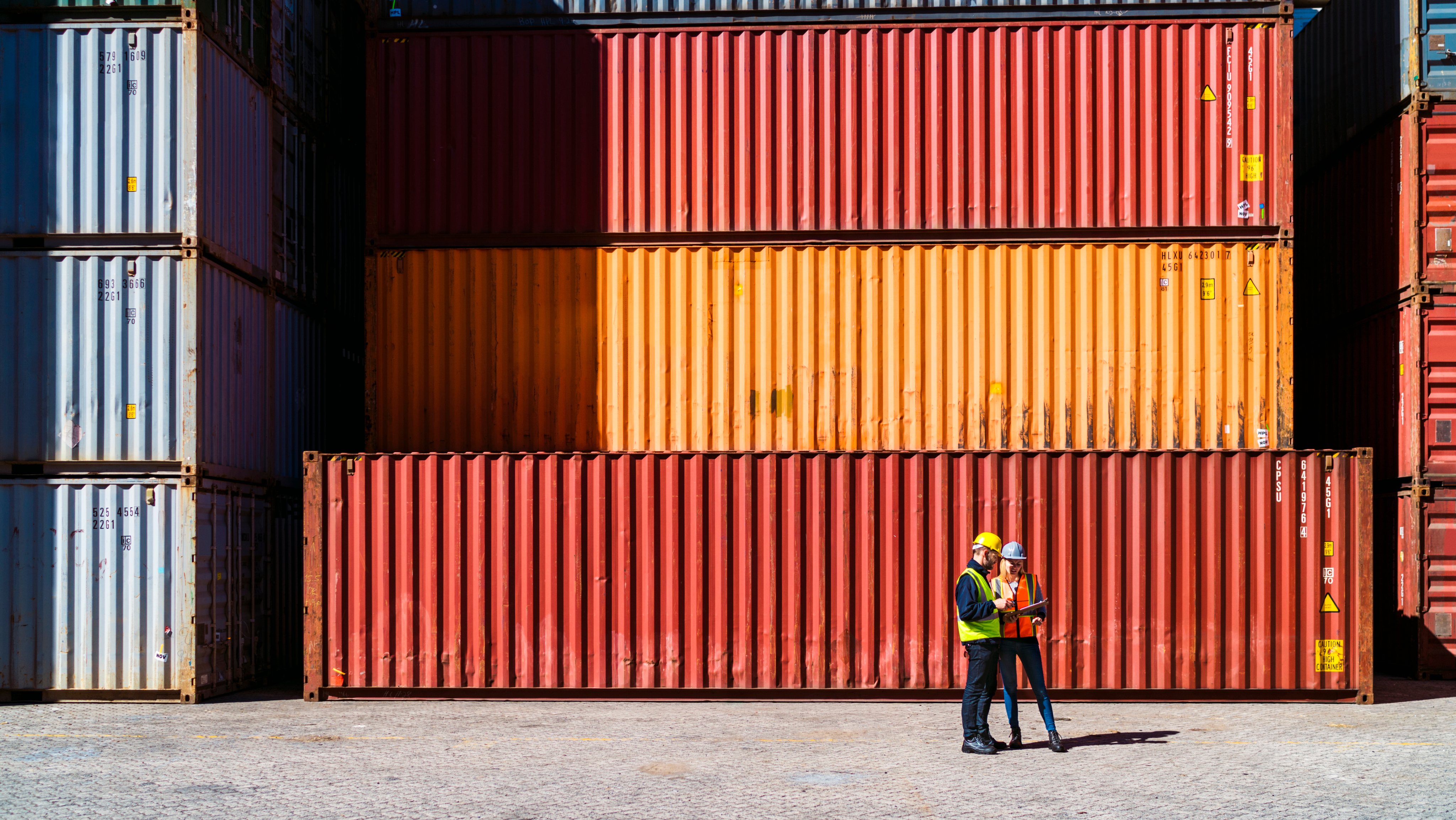 Workers having discussion against cargo containers