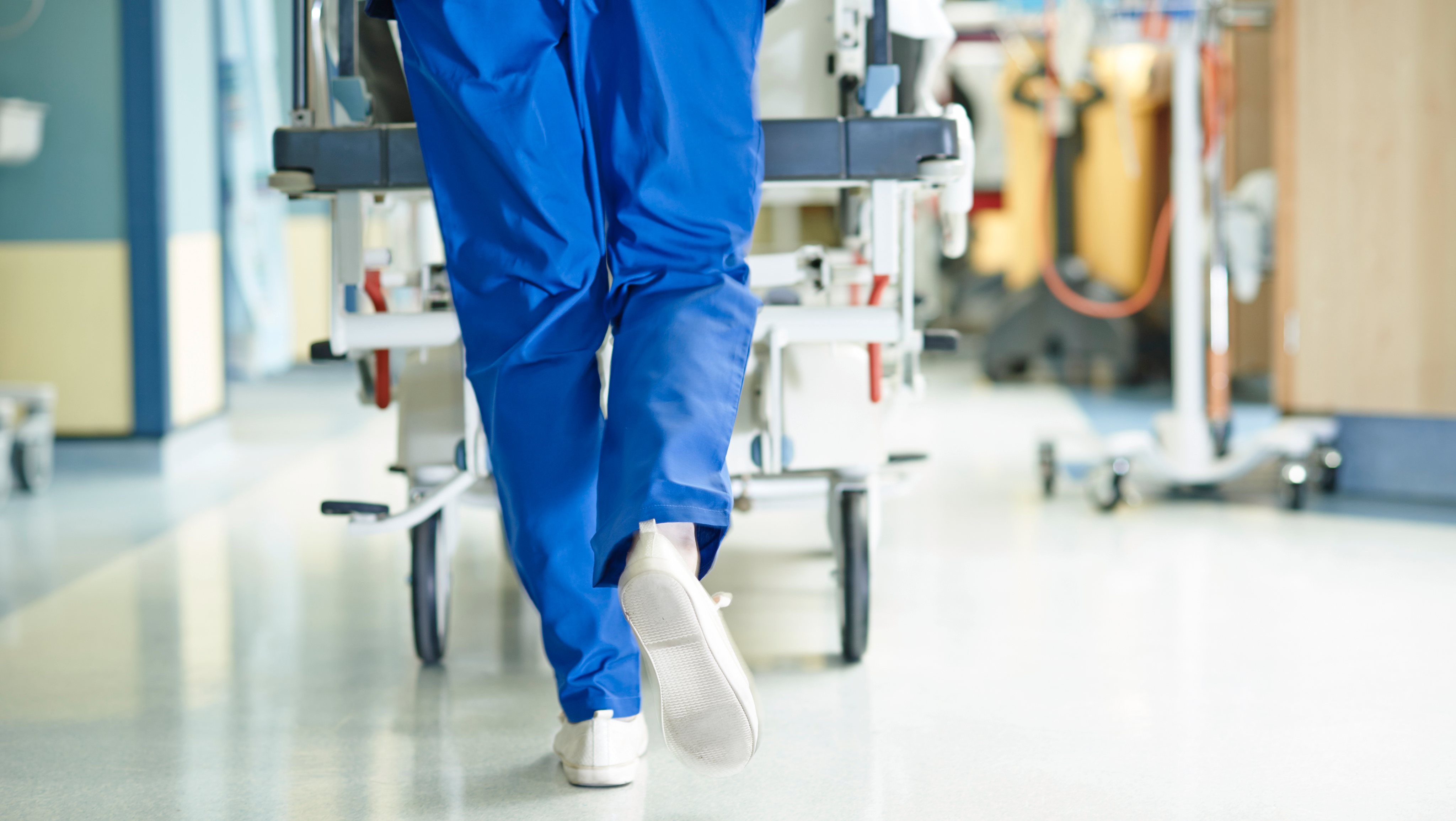 Legs of medic running with gurney along hospital corridor