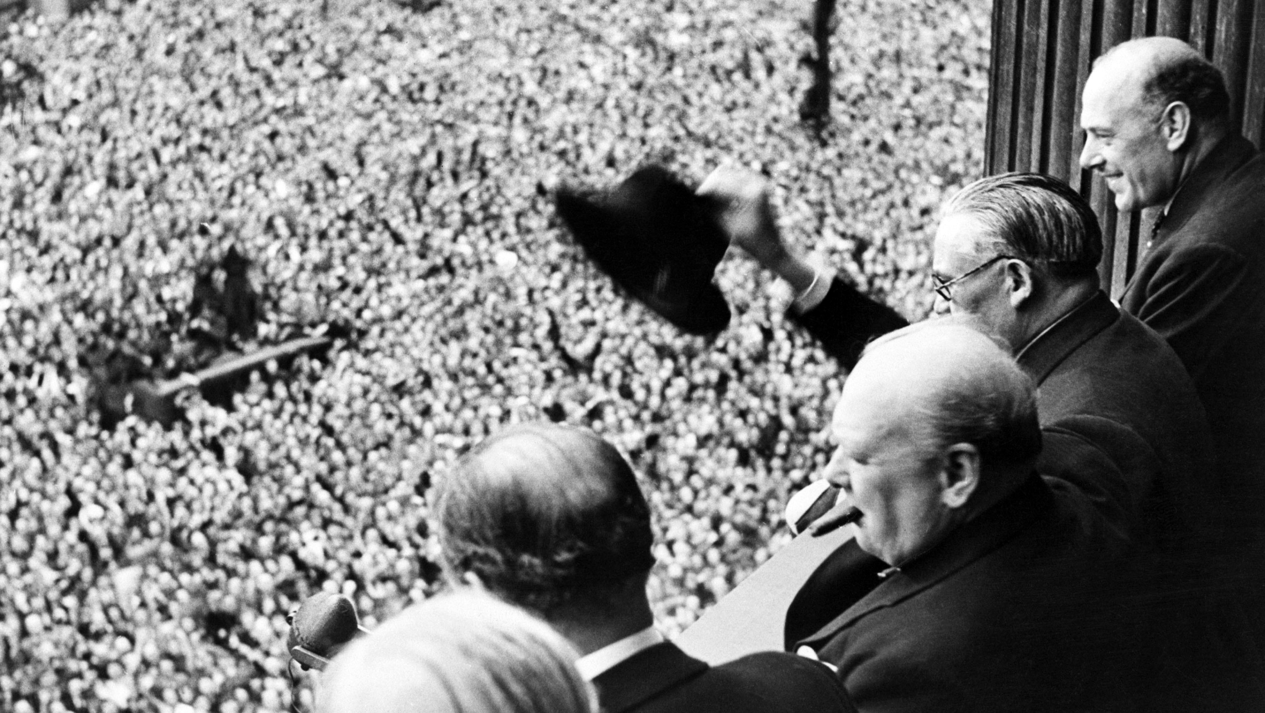 Sir Winston Churchill looking out over crowds celebrating the end of the Second World War in London.
