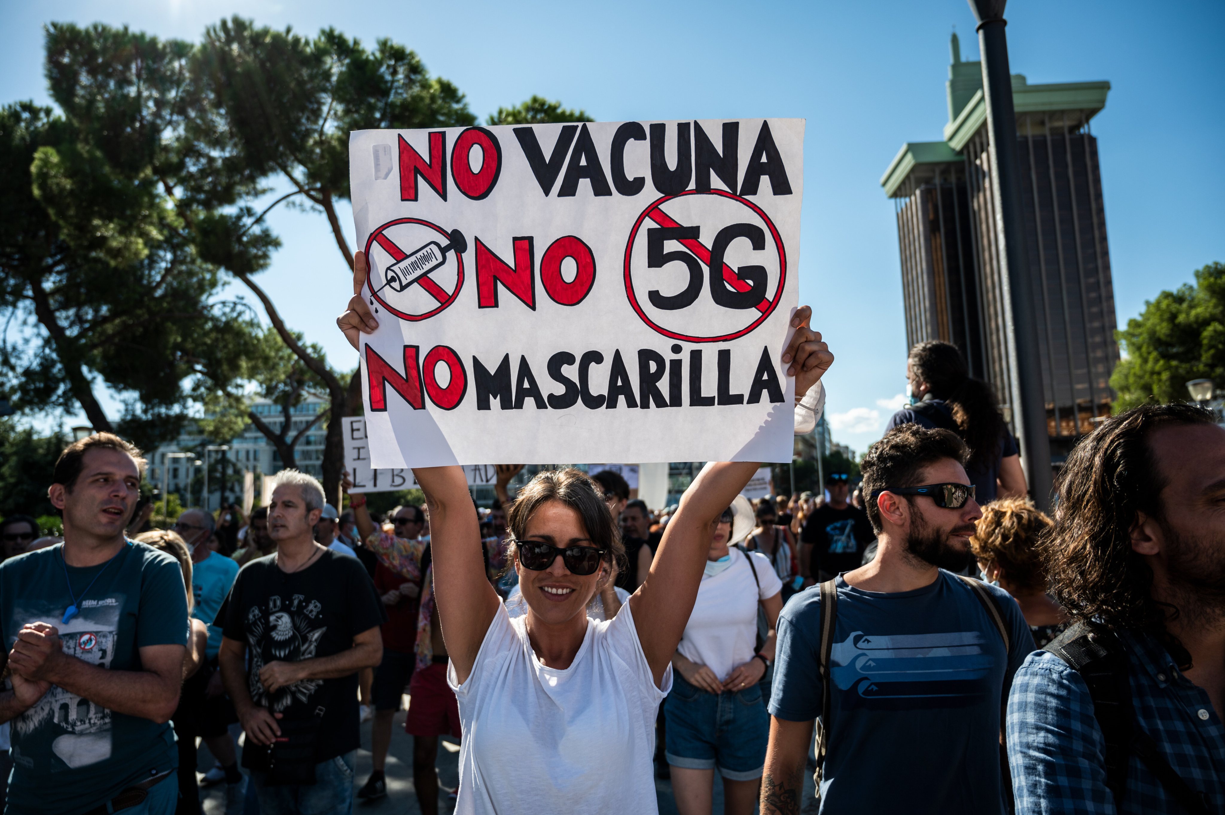 A woman holding a placard against the use of vaccine and 5G