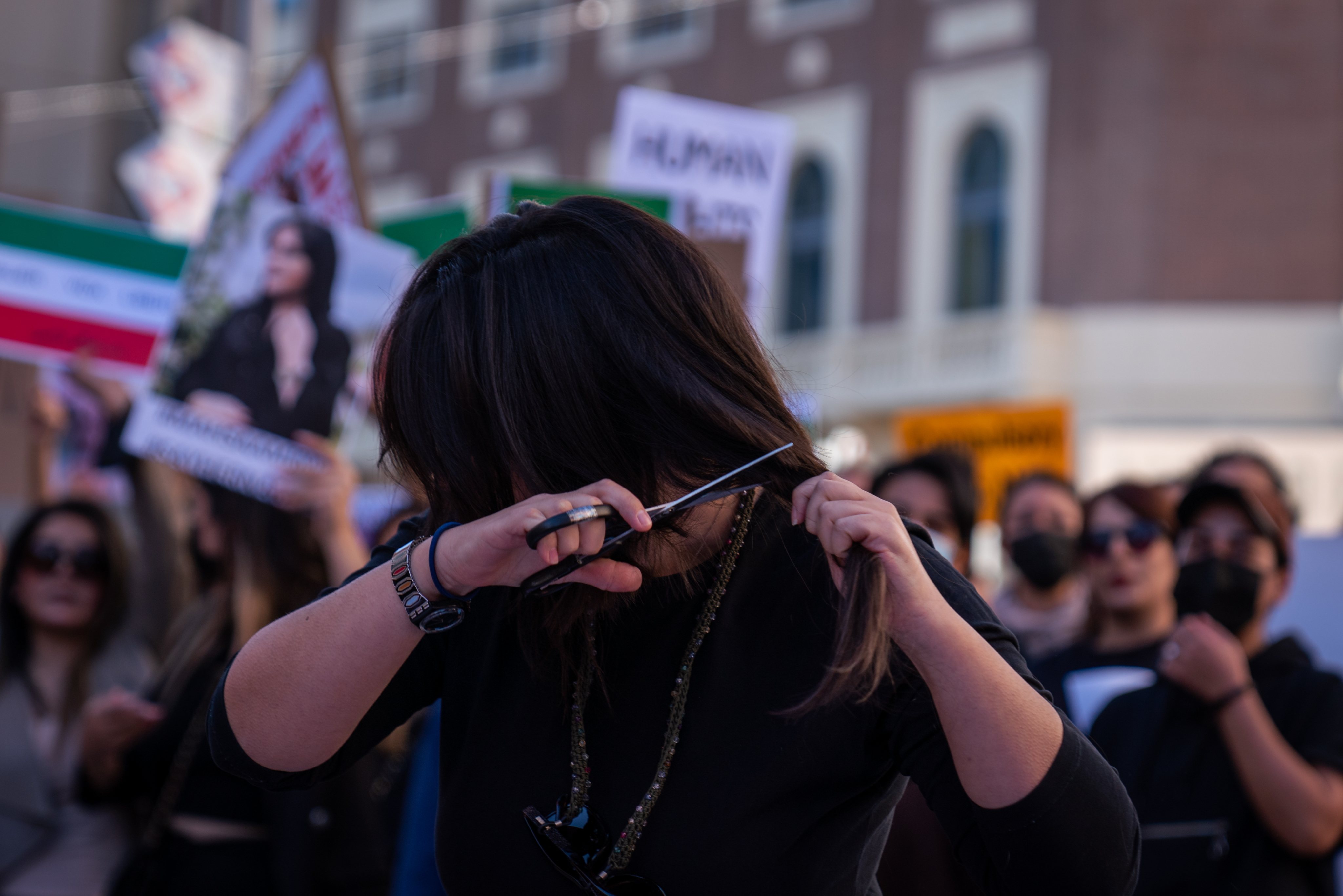 A woman seen cutting off her hair during the demonstration