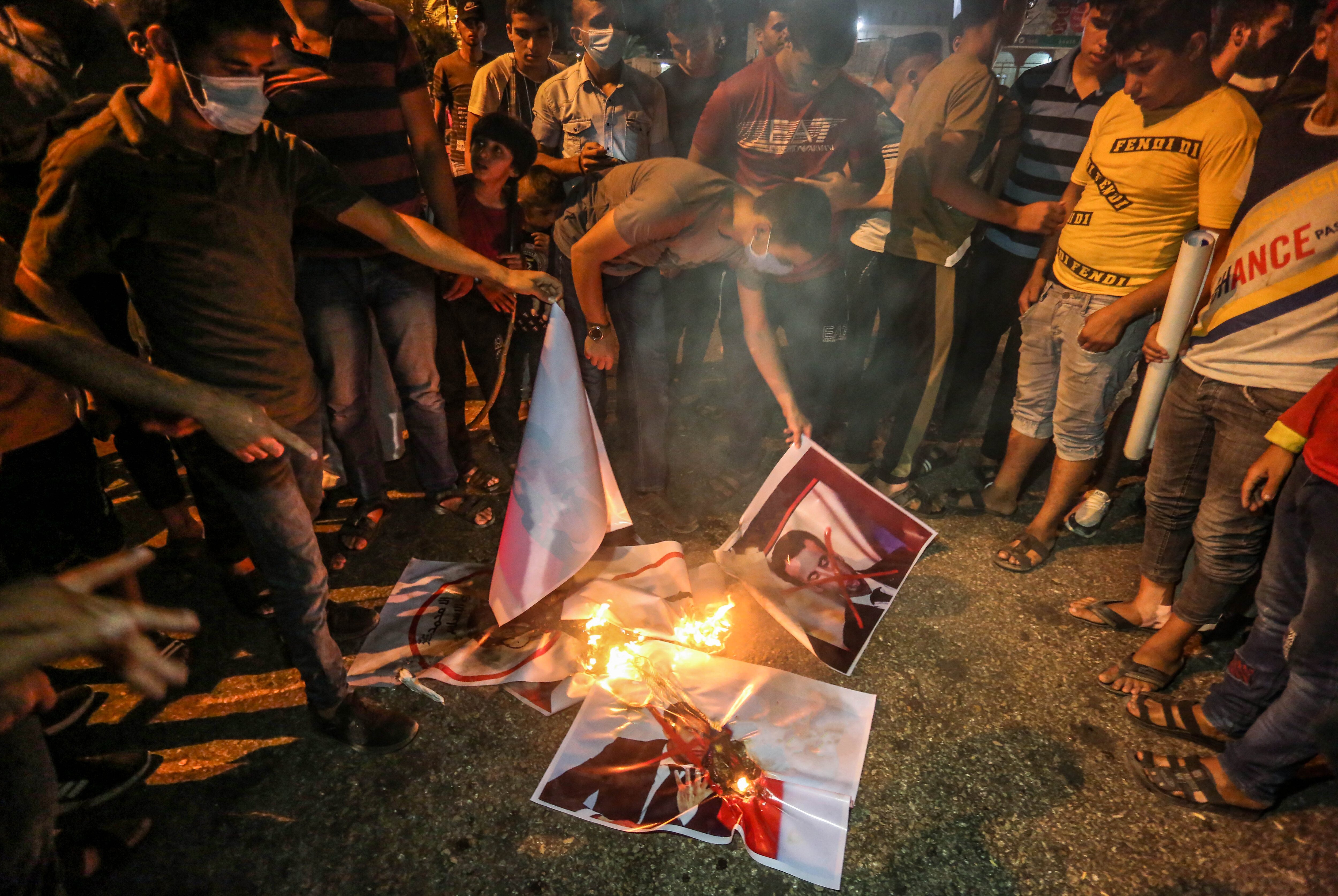 Protesters burning placards with portraits of the French