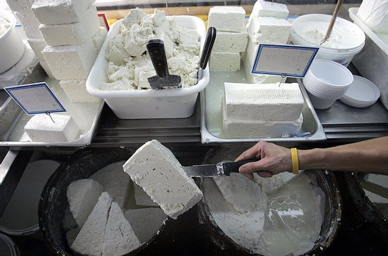 Athens, GREECE:  A shop assistant lifts a slab of feta cheese in Athens, Greece, 25 October 2005. The Greek agriculture ministry 25 October welcomed a ruling by the EU's highest court awarding Greece exclusive rights to the feta cheese brand over claims from producers elsewhere in Europe.    AFP PHOTO / Aris Messinis  (Photo credit should read ARIS MESSINIS/AFP/Getty Images)