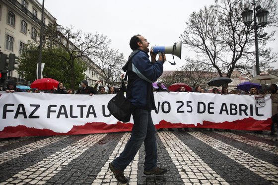 A man shouts slogans in front of a banner reading "A new 25th April is needed"  as he marches with other demonstrators in downtown Lisbon on April 25, 2012, during a demonstration to celebrate the 38th anniversary of the revolution day in Portugal. AFP PHOTO/ PATRICIA DE MELO MOREIRA        (Photo credit should read PATRICIA DE MELO MOREIRA/AFP/GettyImages)