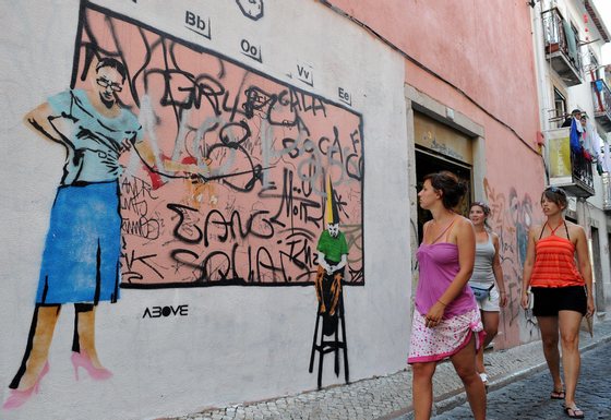 TO GO WITH AFP STORY IN FRENCH BY ANNE LE COZ --- Three bystanders look at a graffiti on the wall of a building of Bairro Alto, on August 15, 2008, a neighbourhood of Lisbon. Several well-known graffiti's artists painted the walls of this bohemian neighbourhood, creating an "Ephemeral Museum".   AFP PHOTO/ FRANCISCO LEONG (Photo credit should read FRANCISCO LEONG/AFP/Getty Images)