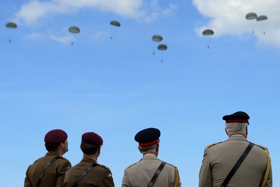 Britain's Prince Charles (C), Prince of Wales, watches as teams of French, US, Canadian and British paratroopers jump from aeroplanes during a D-Day commemoration in Ranville, northern France, on June 5, 2014, on the eve of the 70th anniversary of the World War II Allied landings in Normandy. June 6, 2014 marks the 70th anniversary of D-Day and "Operation Overlord", a vast military operation by Allied forces in Normandy, which turned the tide of World War II, eventually leading to the liberation of occupied France and the end of the war against Nazi Germany.   AFP PHOTO / POOL / LEON NEAL