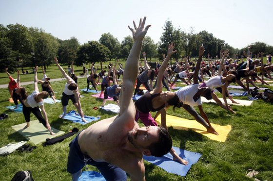 LONDON, UNITED KINGDOM - JULY 26: People take part in a complimentery yoga class at Primrose Hill, on July 26, 2012 in London, England. The South of England continues to enjoy fine weather as the Olympic Games begin this weekend. (Photo by Warrick Page/Getty Images) yoga, exercÃ­cio
