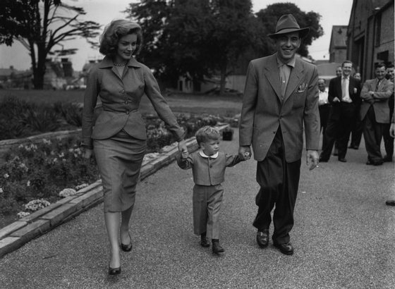 Film star Humphrey De Forest Bogart (1899-1957) and his fourth wife Lauren Bacall walk their son Stevie through the grounds of Isleworth film studios, where he has been working on 'The African Queen'.   (Photo by Central Press/Getty Images)