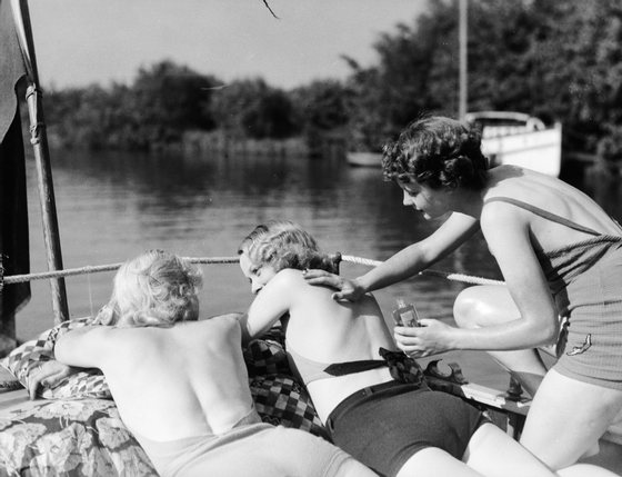 1935:  A boating party apply suntan lotion to protect the skin on their shoulders.  (Photo by Fox Photos/Getty Images)