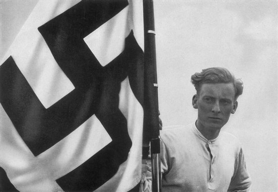 circa 1935:  A member of the Hitler Youth with a swastika flag at a Nazi rally in Germany.  Original Publication: From a series of collectable images published in Germany during the Nazi period, entitled 'Deutschland Erwacht' (Germany Awakes).  (Photo by Hulton Archive/Getty Images)