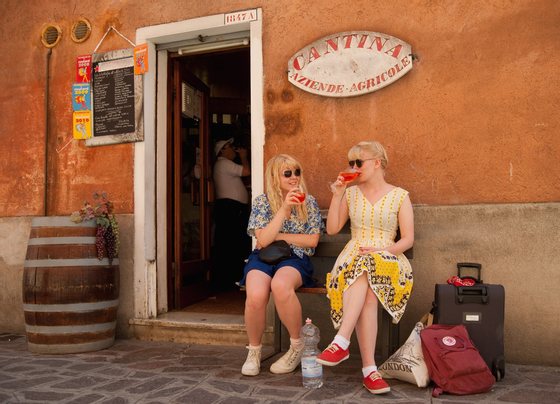 VENICE, ITALY - JUNE 17:  Two tourists enjoy a Spritz (a powerful mixture of white wine, Campari and soda water) in front of a traditiona bacaro on June 17, 2011 in Venice, Italy. The bacari are the local down to earth version of wine bars which serve 'ciccheti, a kind of Tapas traditionally washed down with a glass of wine, and Venetians stop to snack and socialize before and after meals. (Photo by Marco Secchi/Getty Images)