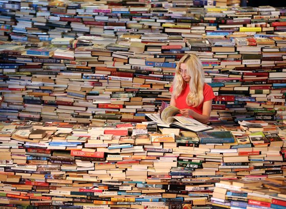 LONDON, ENGLAND - JULY 31:  Employee Tilly Shiner looks at a book in the aMAZEme labyrinth at The Southbank Centre on July 31, 2012 in London, England. Brazilian artists Marcos Saboya and Gualter Pupo used 250,000 books to create the maze which will be on display until August 25, 2012.  (Photo by Peter Macdiarmid/Getty Images)