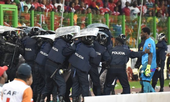 Ghana's national football team players leave the pitch protected by riot police at the half-time of the 2015 African Cup of Nations semi-final football match between Equatorial Guinea and Ghana in Malabo, on February 5, 2015. AFP PHOTO / ISSOUF SANOGO        (Photo credit should read ISSOUF SANOGO/AFP/Getty Images)