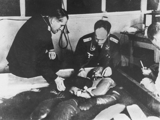 Uma experiÃªncia de imersÃ£o em Ã¡gua gelada no campo de concentraÃ§Ã£o de Dachau, supervisionada por dois mÃ©dicos: o Professor Ernst HolzlÃ¶hner (Ã  esquerda) e o Dr. Sigmund Rascher (Ã  direita).