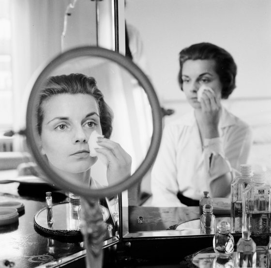 circa 1955:  A woman rubbing her face with cotton wool to remove make up or apply moisturiser.  (Photo by Jacobsen /Three Lions/Getty Images)