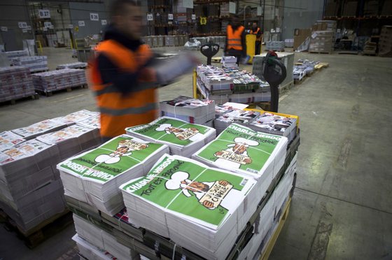 Employees check the arrival of the forthcoming edition of the weekly newspaper Charlie Hebdo, on January 13, 2015 in Villabe, south of Paris, a week after two jihadist gunmen stormed the Paris offices of the satirical magazine, killing 12 people including some of the country's best-known cartoonists. Its cover features the prophet with a tear in his eye, holding a "Je Suis Charlie" sign under the headline "All is forgiven".   AFP PHOTO MARTIN BUREAU        (Photo credit should read MARTIN BUREAU/AFP/Getty Images)