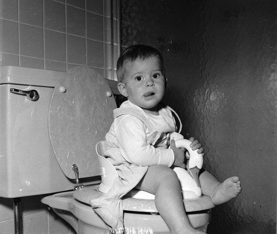 circa 1950:  A one year old learns to use the lavatory with her own special toilet seat.  (Photo by Lloyd Yearwood/Three Lions/Getty Images)