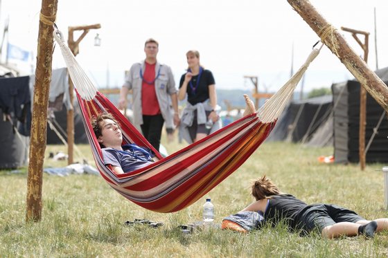 ALMKE, GERMANY - JULY 31:  A scout enjoys the sun in his hammock at the camp on July 31, 2010 in Almke near Wolfsburg, Germany. About 5000 young scouts from Germany, Russia, Belgium, Suisse, USA and Italy aged 12 to 20 participate in a camp. Since 1973, the German VCP-Christian Guides and Pathfinders organisation, offers an International historic boys and girls scout meeting during the summer holidays. On a 25 hectare field include 1370 tens, a tent church and a tent theater. The Federal camp is held every four years.  (Photo by Andreas Rentz/Getty Images)