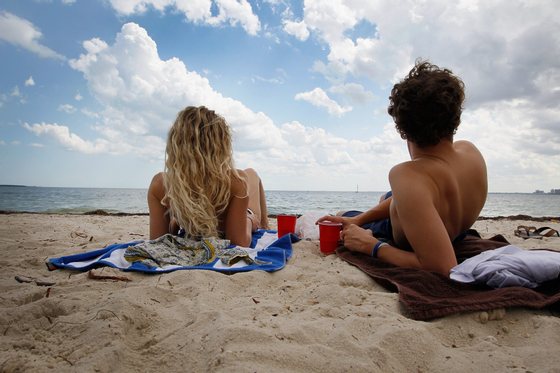 KEY BISCAYNE, FL - MAY 10:  Lia Calavro (L) and Jamie Sadler sit in the sun while laying on the beach on May 10, 2012 in Key Biscayne, Florida. The Center for Disease Control and Prevention released a report that indicated that although protective behaviors such as sunscreen use, shade use, and wearing long clothing to the ankles have increased in recent years, sunburn prevalence remains high, with 50.1% of all adults and 65.6% of whites aged 18-29 years reporting at least one sunburn in the past 12 months.  (Photo by Joe Raedle/Getty Images)