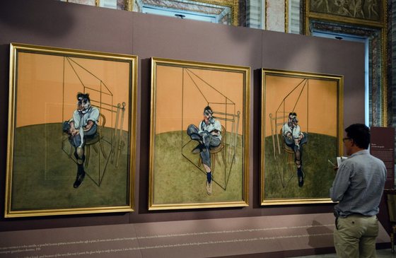 TO GO WITH AFP STORY: Face Ã  face d'anthologie Ã  Rome entre Le Caravage et Francis Bacon A Journalist looks at Francis Bacon's paintings " Three Studies of Lucian Freud - 1969 " during the opening of the exhibition 'Caravaggio and Bacon' at the Borghese museum in Rome on September 30, 2009. The exhibition runs until January 24, 2010.        AFP PHOTO / VINCENZO PINTO (Photo credit should read VINCENZO PINTO/AFP/Getty Images)
