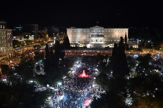 People gather in front of the Greek Parliament in Athens on July 5, 2015, after early results showed those who rejected further austerity measures in a crucial bailout referendum were poised to win. Over 61 percent of Greek voters on July 5 rejected fresh austerity demands by the country's EU-IMF creditors in a historic referendum, official results from 50 percent of polling stations showed.  AFP PHOTO / ARIS MESSINIS        (Photo credit should read ARIS MESSINIS/AFP/Getty Images)