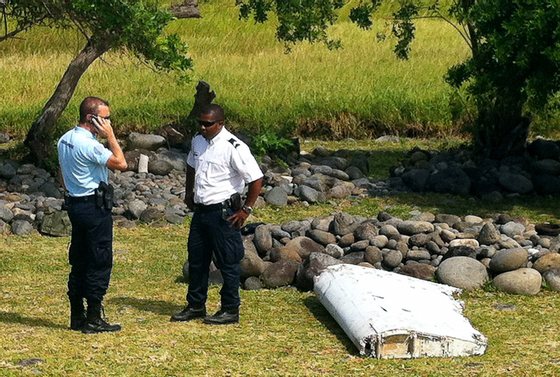 A policeman and a gendarme stand next to a piece of debris from an unidentified aircraft found in the coastal area of Saint-Andre de la Reunion, in the east of the French Indian Ocean island of La Reunion, on July 29, 2015. The two-metre-long debris, which appears to be a piece of a wing, was found by employees of an association cleaning the area and handed over to the air transport brigade of the French gendarmerie (BGTA), who have opened an investigation. An air safety expert did not exclude it could be a part of the Malaysia Airlines flight MH370, which went missing in the Indian Ocean on March 8, 2014. AFP PHOTO / YANNICK PITOU (Photo credit should read YANNICK PITOU/AFP/Getty Images)