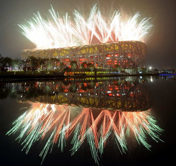 Fireworks explode next to the National Stadium, also known as the "Bird's Nest",  during the opening ceremony of the 2008 Beijing Olympic Games on August 8, 2008.  A thundering display of fireworks exploded over the "Bird's Nest" stadium in the shape of a blossoming red flower as China put the full glory of its rich history on display at the Olympic opening ceremony. Some 91,000 people, many waving Chinese flags, packed into the National Stadium on a hot and humid night for a spectacular show masterminded by Oscar-nominated filmmaker Zhang Yimou.       AFP PHOTO / FRANCK FIFE (Photo credit should read FRANCK FIFE/AFP/Getty Images)