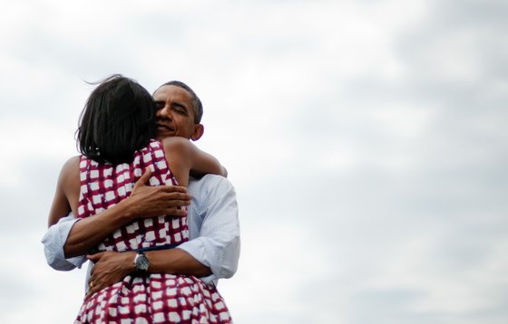 First Lady Michelle Obama (L) and US President Barack Obama (R) hug after delivering remarks during a campaign event at the Alliant Energy Amphitheater in Dubuque, Iowa, August 15, 2012, during his three-day campaign bus tour across the state. AFP PHOTO/Jim WATSON (Photo credit should read JIM WATSON/AFP/Getty Images)