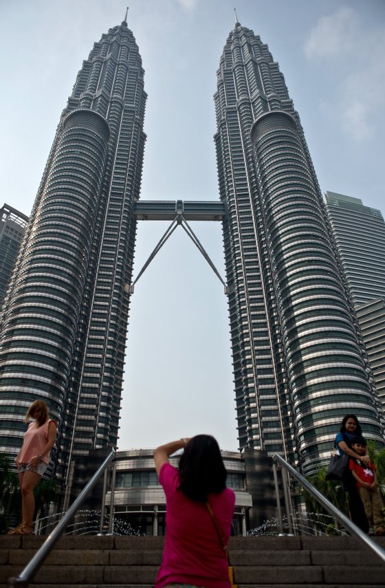 To go with Ukraine-Russia-crisis-aviation-Malaysia-tourism,FOCUS by Bhavan Jaipragas Tourists pose at the Petronas Twin Towers in Kuala Lumpur on July 23, 2014. An unprecedented second major aviation disaster in four months could further associate Malaysia with calamity in the eyes of travellers, observers warn, putting the tropical destination's vital tourism sector at risk. AFP PHOTO/ MANAN VATSYAYANA (Photo credit should read MANAN VATSYAYANA/AFP/Getty Images)