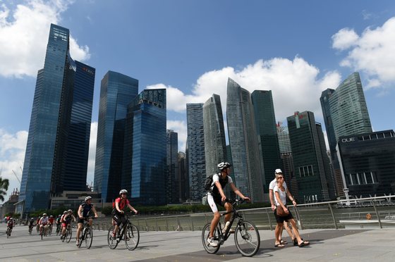 A group of Westerners ride their bicycles along the promenade at Marina Bay in Singapore on January 13, 2015. The New York Times recently published its "52 Places to go in 2015", and Singapore came in at number six on their list, Singapore media reported online. AFP PHOTO / ROSLAN RAHMAN (Photo credit should read ROSLAN RAHMAN/AFP/Getty Images)