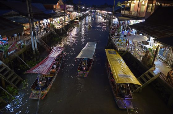This picture taken on March 28, 2015 shows boats carrying visitors along the Amphawa canal, a small tributary of the Mae Khlong River, in Samut Songkhram province some 80 kilometers west of Bangkok. The canal turns into a floating market every weekend when crowds of Bangkokians flock to feast on bargain seafood. The visitors fill every inch of the steps surrounding the canal to pick out crabs, squids, clams, fish or shrimps from moored boats fully kitted with stoves and kitchen utensils. Cooks roast their catch in the open air before waiters carefully carry plates of food along boat edges to their customers. Others stay put, delicately swinging their freshly prepared meals in baskets hanging from long bamboo sticks directly onto tables. AFP PHOTO / Christophe ARCHAMBAULT (Photo credit should read CHRISTOPHE ARCHAMBAULT/AFP/Getty Images)
