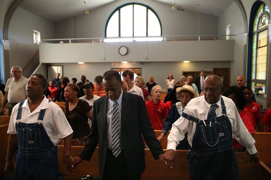 DES MOINES, IA - AUGUST 16: Republican presidential hopeful Ben Carson (C) prays during church services at Maple Street Missionary Baptist Church on August 16, 2015 in Des Moines , Iowa. Ben Carson attended Sunday church services before campaigning at the Iowa State Fair. (Photo by Justin Sullivan/Getty Images)