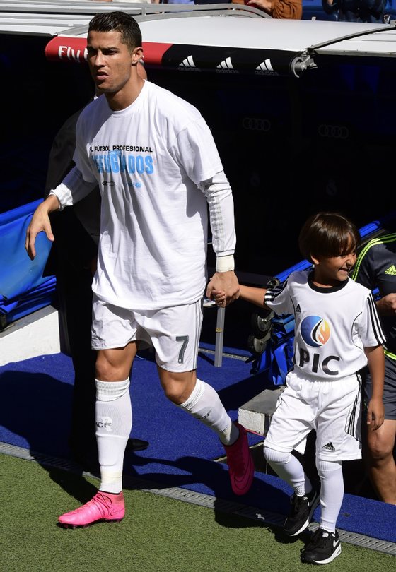 Real Madrid's Portuguese forward Cristiano Ronaldo (L) enters the pitch with Zaid, son of Osama Abdul Mohsen (C), the Syrian refugee who made world headlines when a Hungarian journalist tripped him over as he fled, before the Spanish league football match Real Madrid CF vs Granada FC at the Santiago Bernabeu stadium in Madrid on Spetember 19, 2015. AFP PHOTO/ JAVIER SORIANO (Photo credit should read JAVIER SORIANO/AFP/Getty Images)