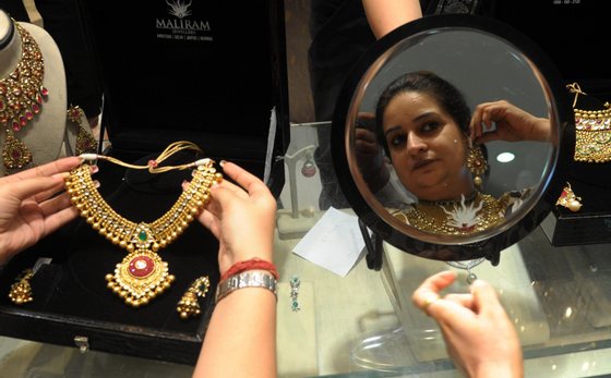 Indian shoppers try on gold jewellery at a jewellery store on Dhanteras in Amritsar on October 21, 2014. Dhanteras, which happens two days before the Hindu festival Diwali, is seen as an auspicious day to make purchases. AFP PHOTO/NARINDER NANU (Photo credit should read NARINDER NANU/AFP/Getty Images)