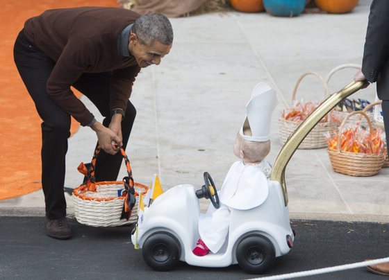 US President Barack Obama greets a young child dressed as the Pope and riding in a "Popemobile" as he hands out treats to children trick-or-treating for Halloween on the South Lawn of the White House in Washington, DC, October 30, 2015. AFP PHOTO / SAUL LOEB (Photo credit should read SAUL LOEB/AFP/Getty Images)