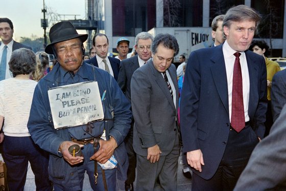 US developer Donald Trump (R) walks down Fifth Avenue past a beggar after holding a news conference on November 16, 1990. Trump announced he had reached a deal that will temporarily force his Taj Mahal casino into bankruptcy court. AFP PHOTO TIMOTHY A. CLARY (Photo credit should read TIMOTHY A. CLARY/AFP/Getty Images)